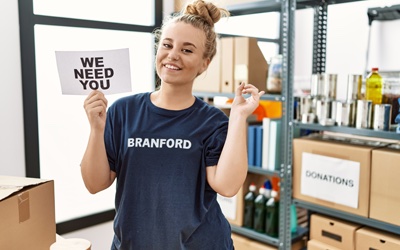 A volunteer holding a sign that says 'We Need You'