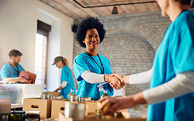 A volunteer welcomes a colleague while packing boxes